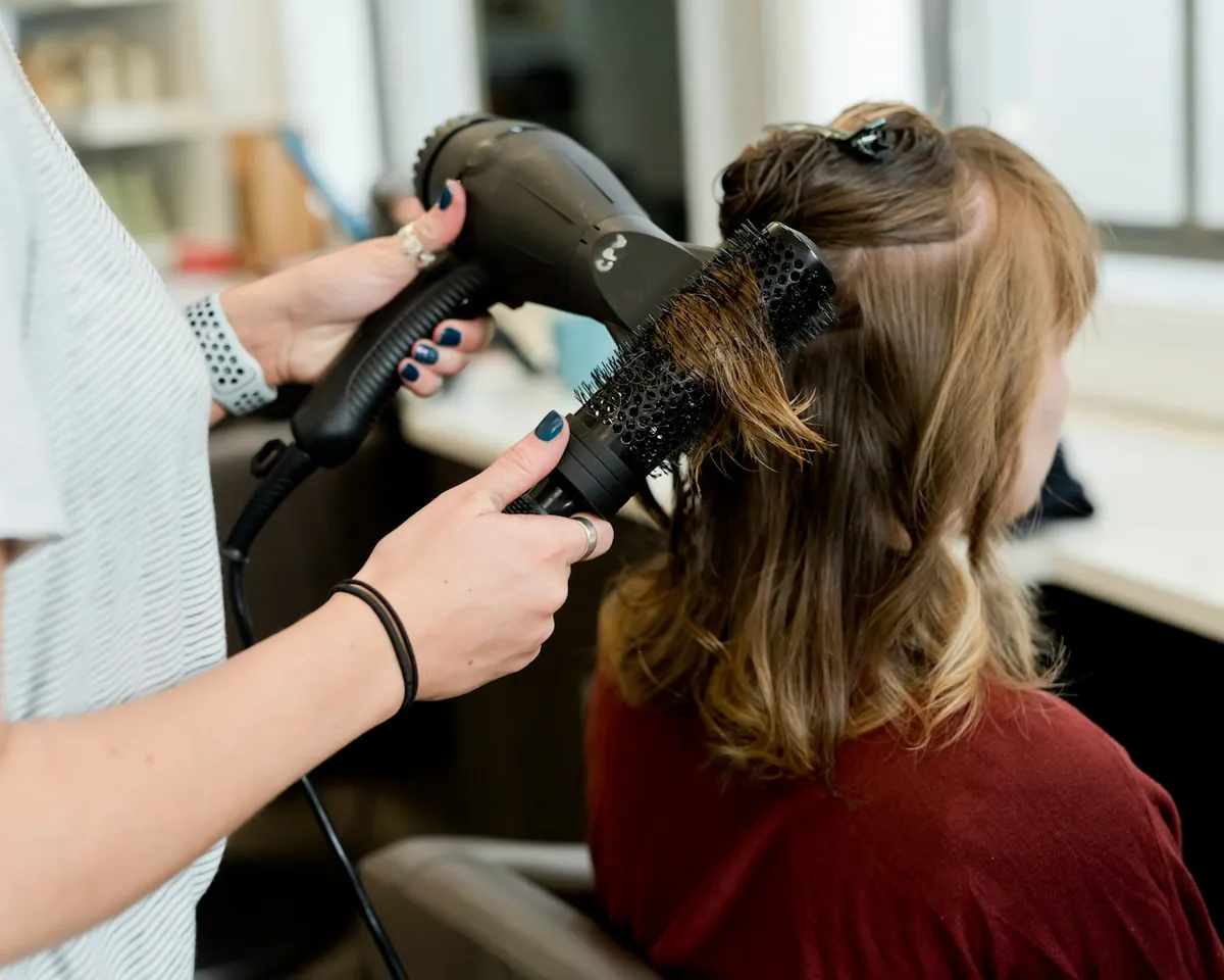 A stylist blow-drying a regular client's hair