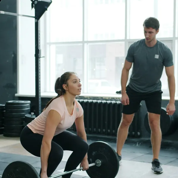 A personal trainer coaching a client through a lift